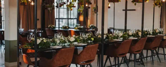 Ein festlich gedeckter Tisch mit Blumen und hängenden Pflanzen in einem modernen, gemütlich beleuchteten Raum.